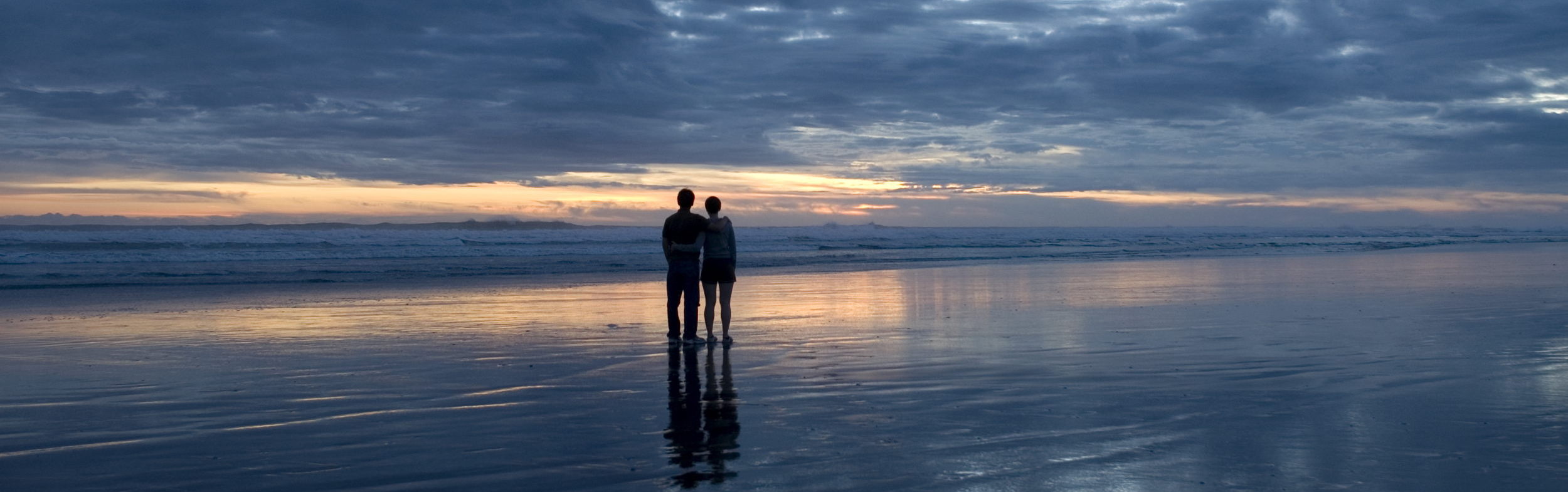 Two people on beach after sunset